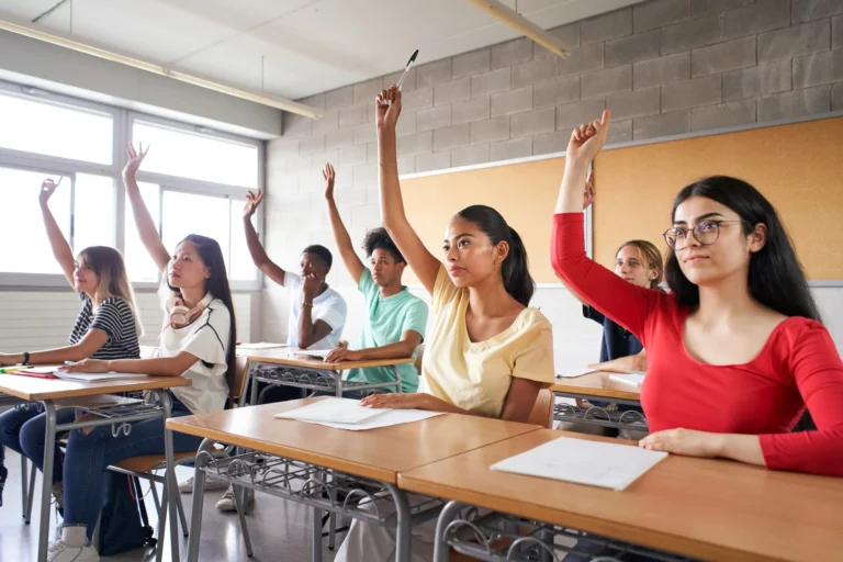 Multi-ethnic students in class with hands raised